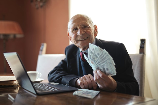 an elderly person smiling and holding money out
